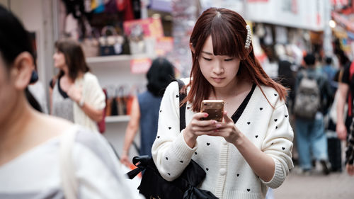 Young woman using mobile phone in city