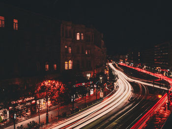 High angle view of light trails on road amidst buildings at night