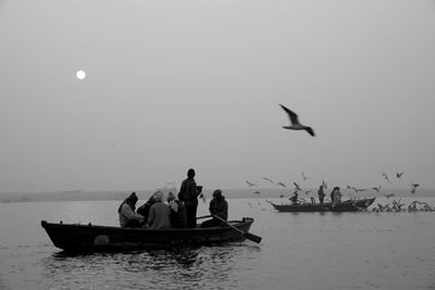 People on boat in sea against sky