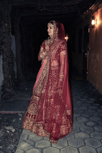 Woman standing on illuminated street at night