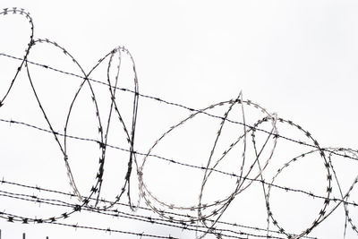 Low angle view of barbed wire against clear sky