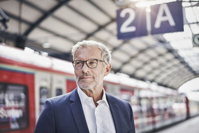 Businessman contemplating while standing at railroad station