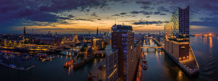 Panoramic view of illuminated buildings against sky during sunset