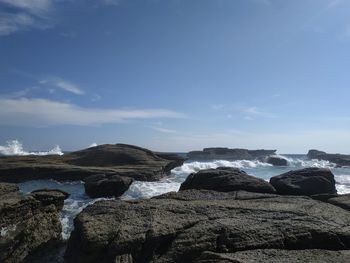 Scenic view of rocks on beach against sky