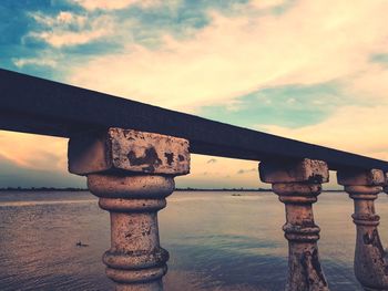 Bridge over sea against sky during sunset