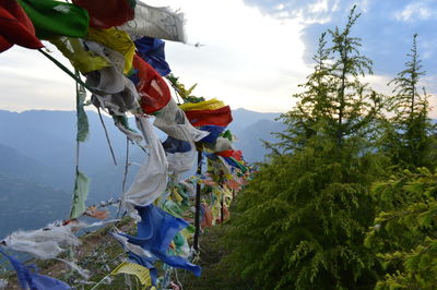 Buddhist flags hanging on railing at mountain against sky