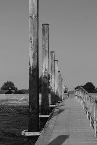 Wooden posts on footpath against sky