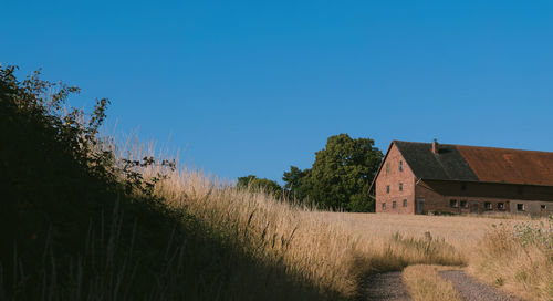 House on field against clear blue sky