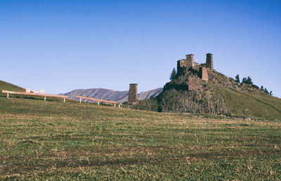 Built structure on field against clear blue sky