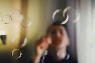 Close-up of young woman holding curtain at home