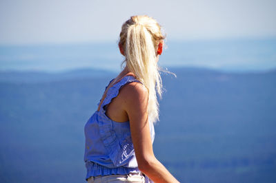 Woman sitting against sky in sunny day