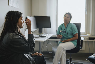 Young woman explaining female physician while sitting in clinic