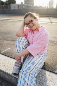 Smiling teenager with down syndrome sitting on footpath