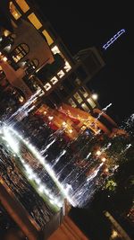 Low angle view of illuminated city against sky at night