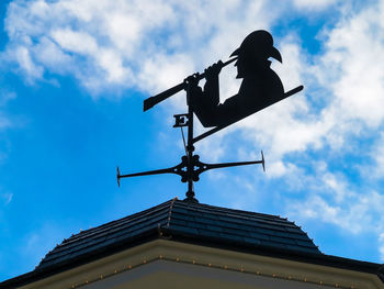 Low angle view of weather vane against building