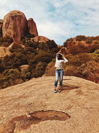 Rear view of man standing on rock against sky