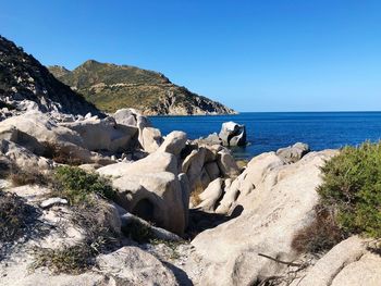 Rocks on beach against clear blue sky