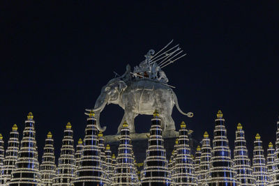 Low angle view of statue against buildings at night