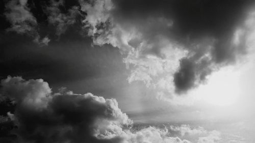 Low angle view of sunlight streaming through clouds