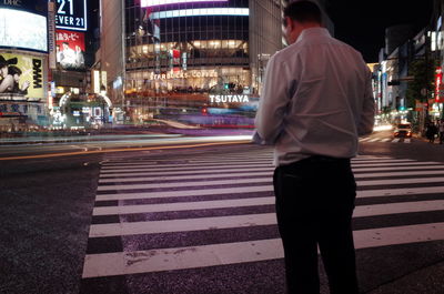 Full length of woman walking on sidewalk in city at night