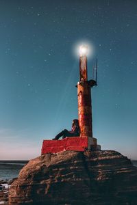 Lighthouse by sea against sky at night