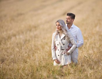 Thoughtful young couple standing on grassy field