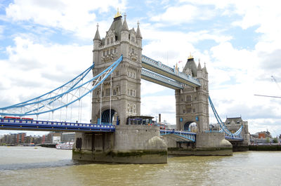 Low angle view of bridge over river against cloudy sky