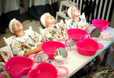 Girls with facial mask relaxing by table at spa