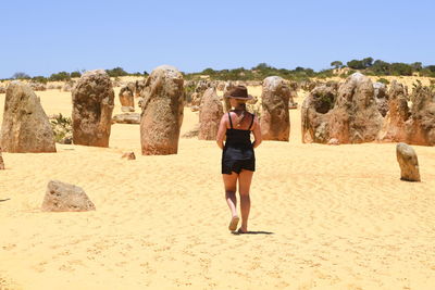 Full length of man standing on rock against clear sky