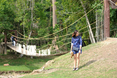 Woman standing on field against trees