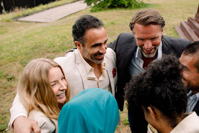 Smiling male and female business professionals huddling in lawn