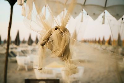 Close-up of white tied hanging from glass