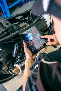 Mature mechanic using digital tablet by motorcycle in garage