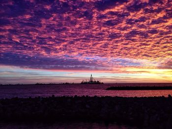 Scenic view of sea against cloudy sky at sunset