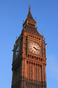 Low angle view of clock tower against blue sky