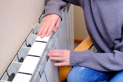 Midsection of woman sitting by heater