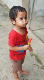 Cute boy eating flavored ice on footpath