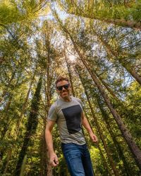 Low angle view of young man standing in forest