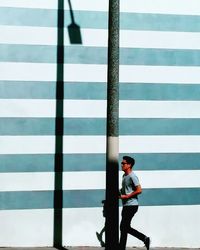 Side view of man standing against white wall