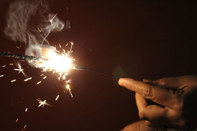 Midsection of woman with fire crackers at night