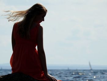 Woman standing by sea against sky