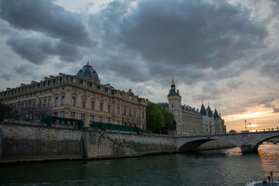 Arch bridge over river against cloudy sky