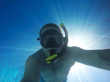 Man swimming in sea against blue sky