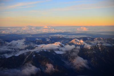 Aerial view of snowcapped mountains against sky during sunset