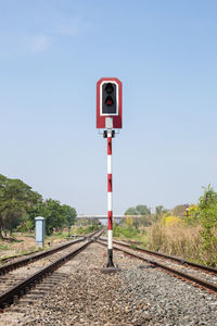 Information sign by railroad tracks against clear sky