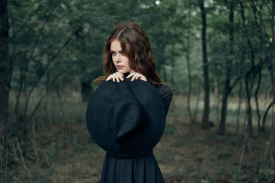 Side view of young woman standing in forest