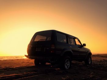 Vintage car on land against sky during sunset