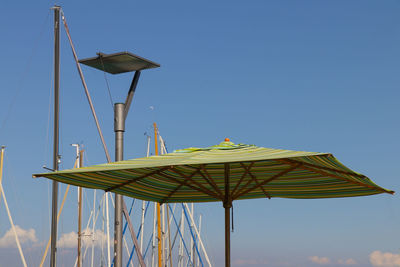 Low angle view of umbrellas against clear blue sky
