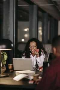 Woman using mobile phone while sitting on table