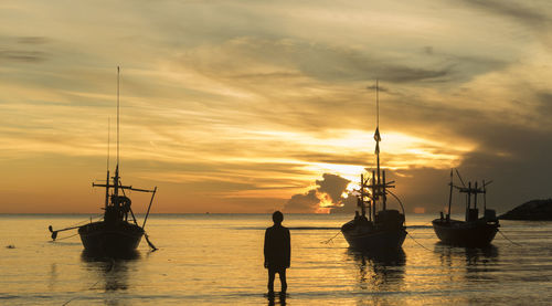 Silhouette fishing sailboats in sea against sky during sunset